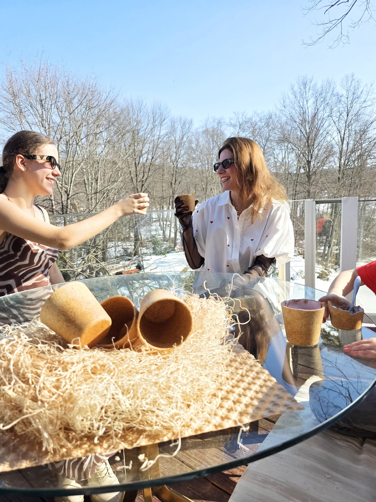 Two women sitting at a table outdoors, enjoying a sunny day.
