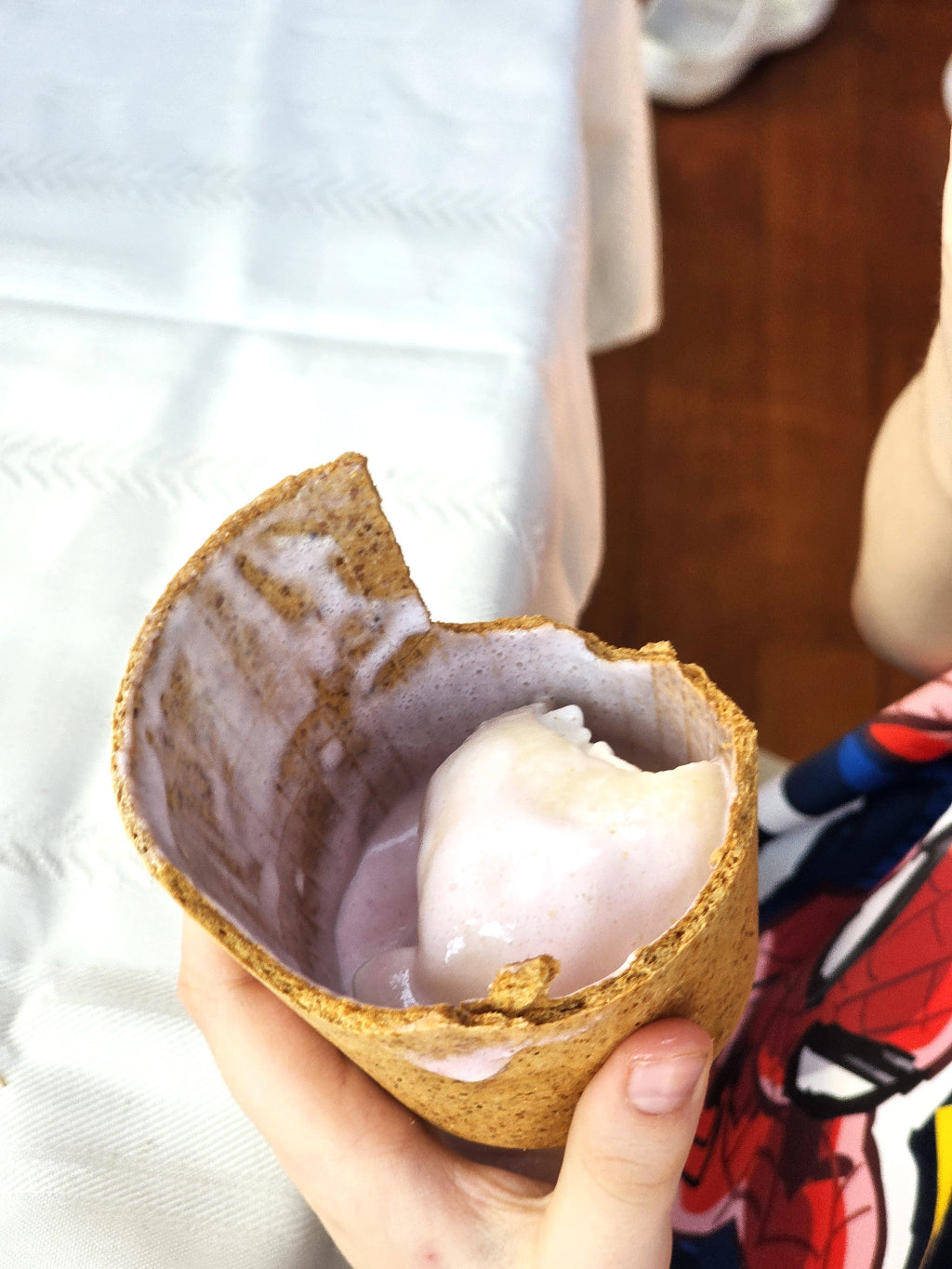 Person holding a half-eaten ice cream cone with a white filling