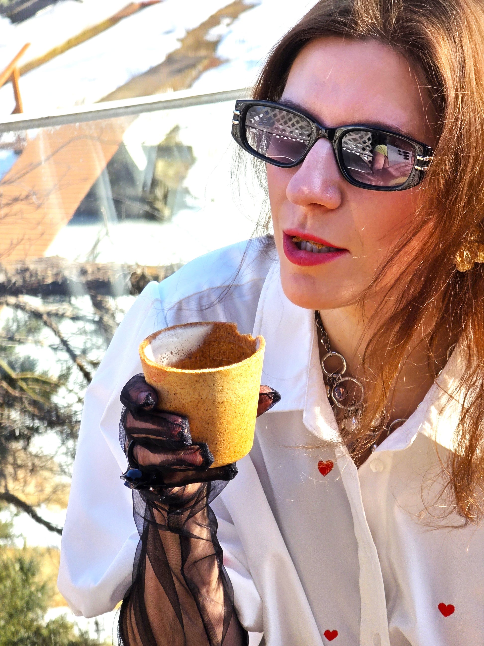 Woman holding a small yellow cup outdoors with a blurred background